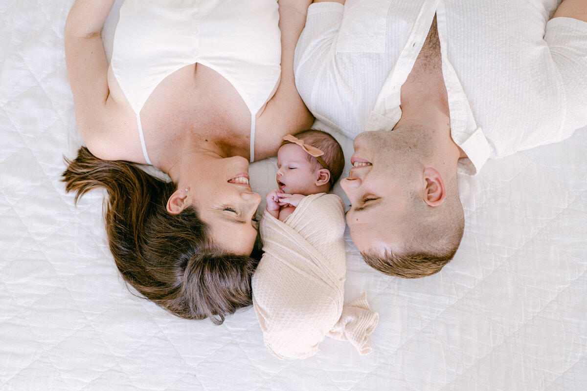 Newborn baby on the bed with her parents