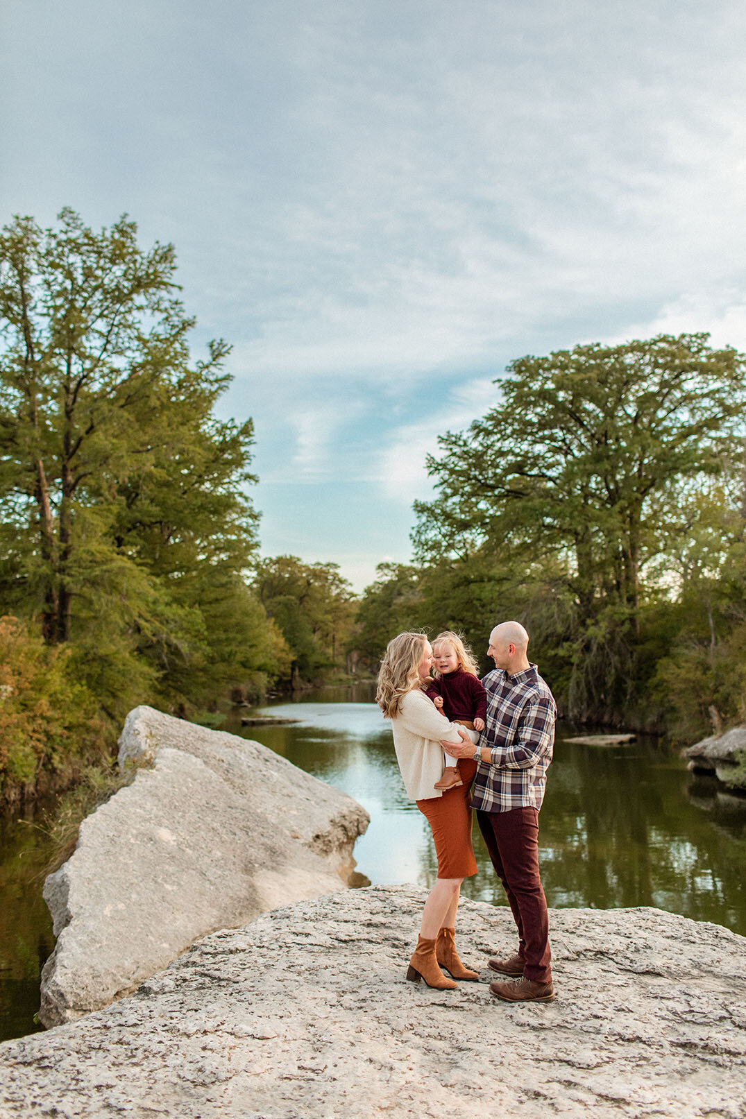 Family portrait by a river with soft, natural light, captured by Sara James in San Antonio.