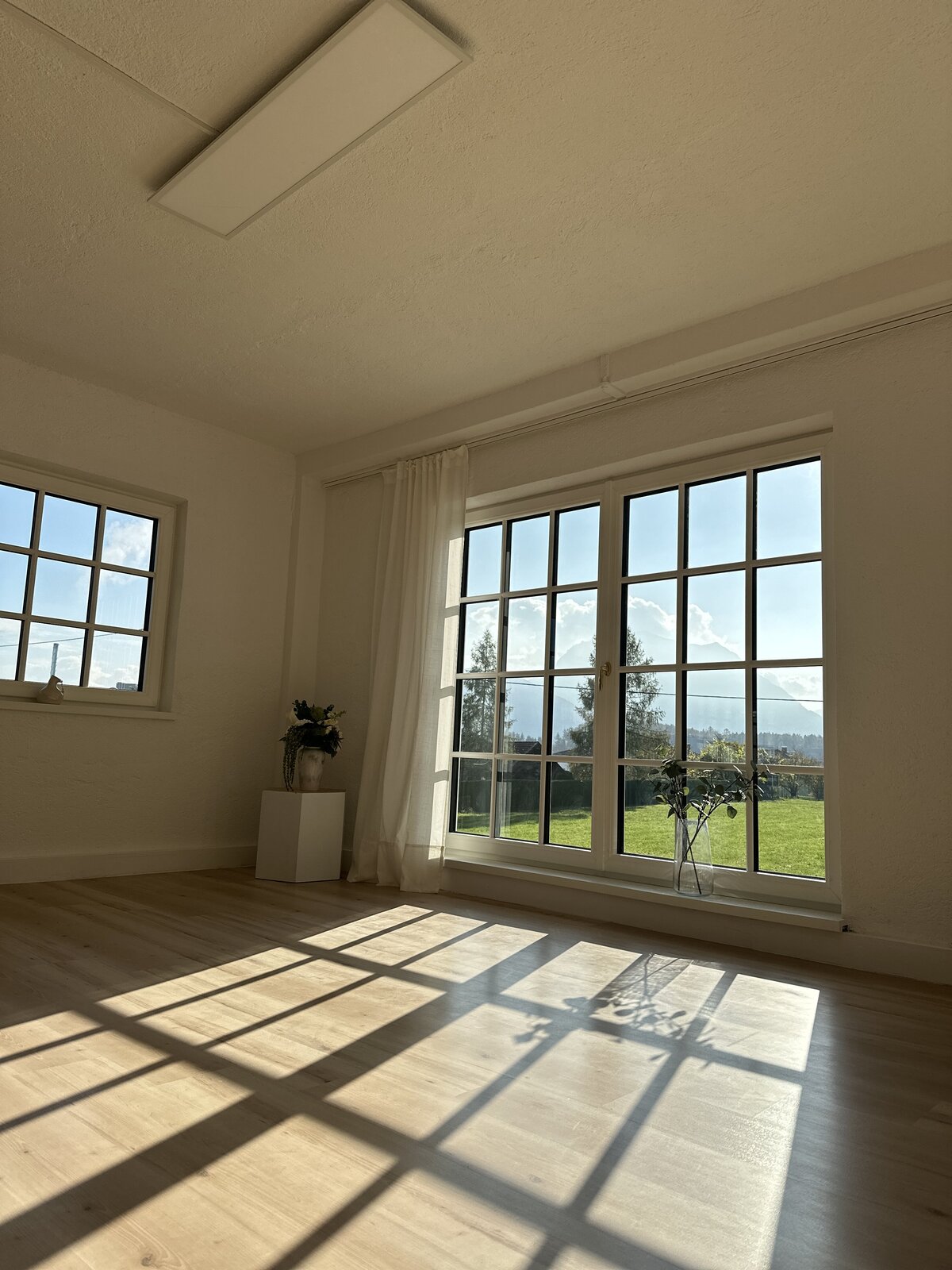Bodentiefe Sprossenfenster im Atelier April, die reichlich Tageslicht hereinlassen und eine einladende Atmosphäre schaffen.