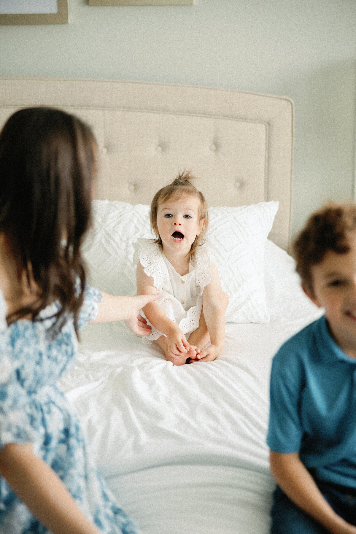 candid photo of mother with older siblings in master bedroom
