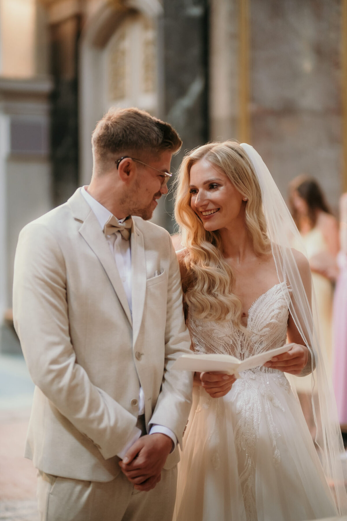 During the wedding ceremony in a church bride and groom look at each other, smiling.