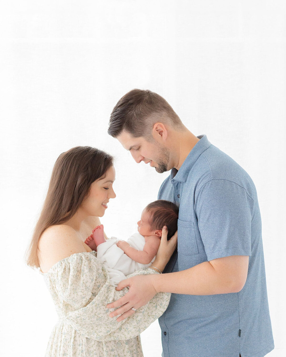 mom and dad hold newborn baby