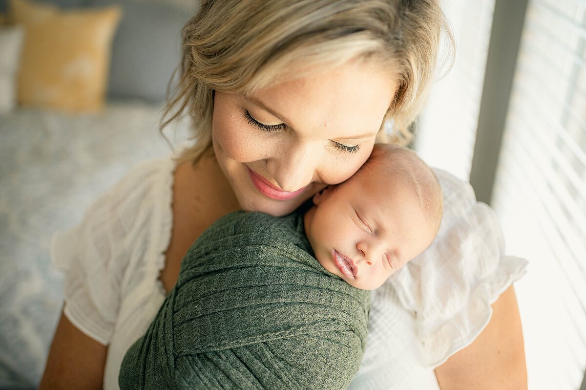 Mom snuggling swaddled baby at their Houston Newborn Photography session
