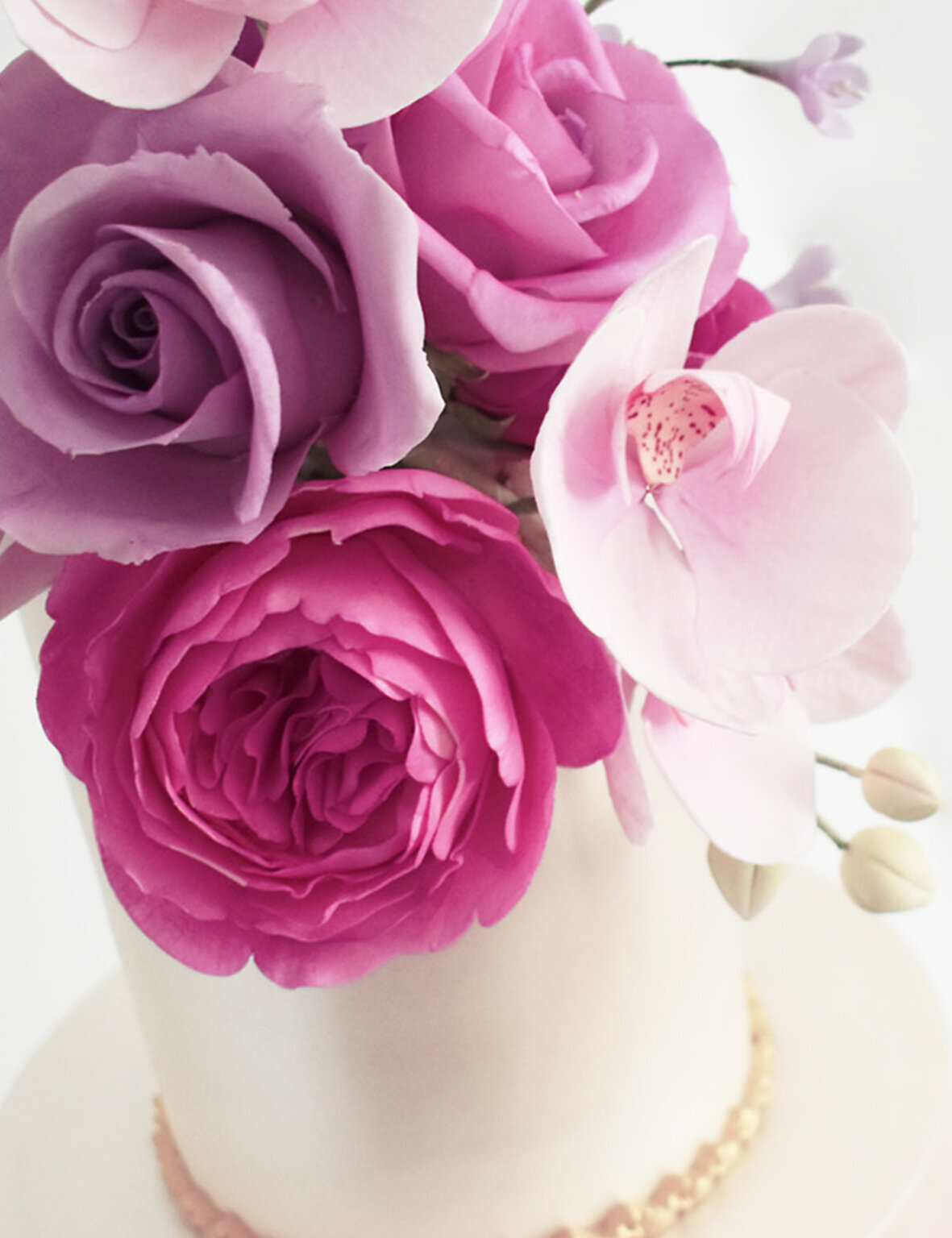 Vibrant pink and lilac sugar flowers on a wedding cake