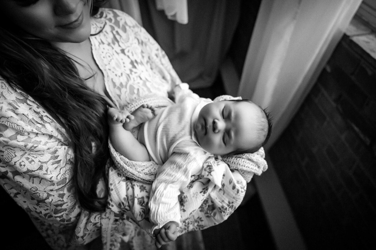 black and white photo of a small baby and his mother. She is holding him while she contemplates his face