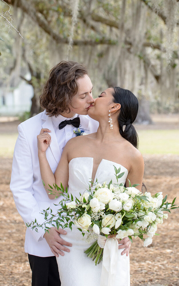 Classic wedding photo of a bride and groom kissing under mossy oak trees in St Augustine