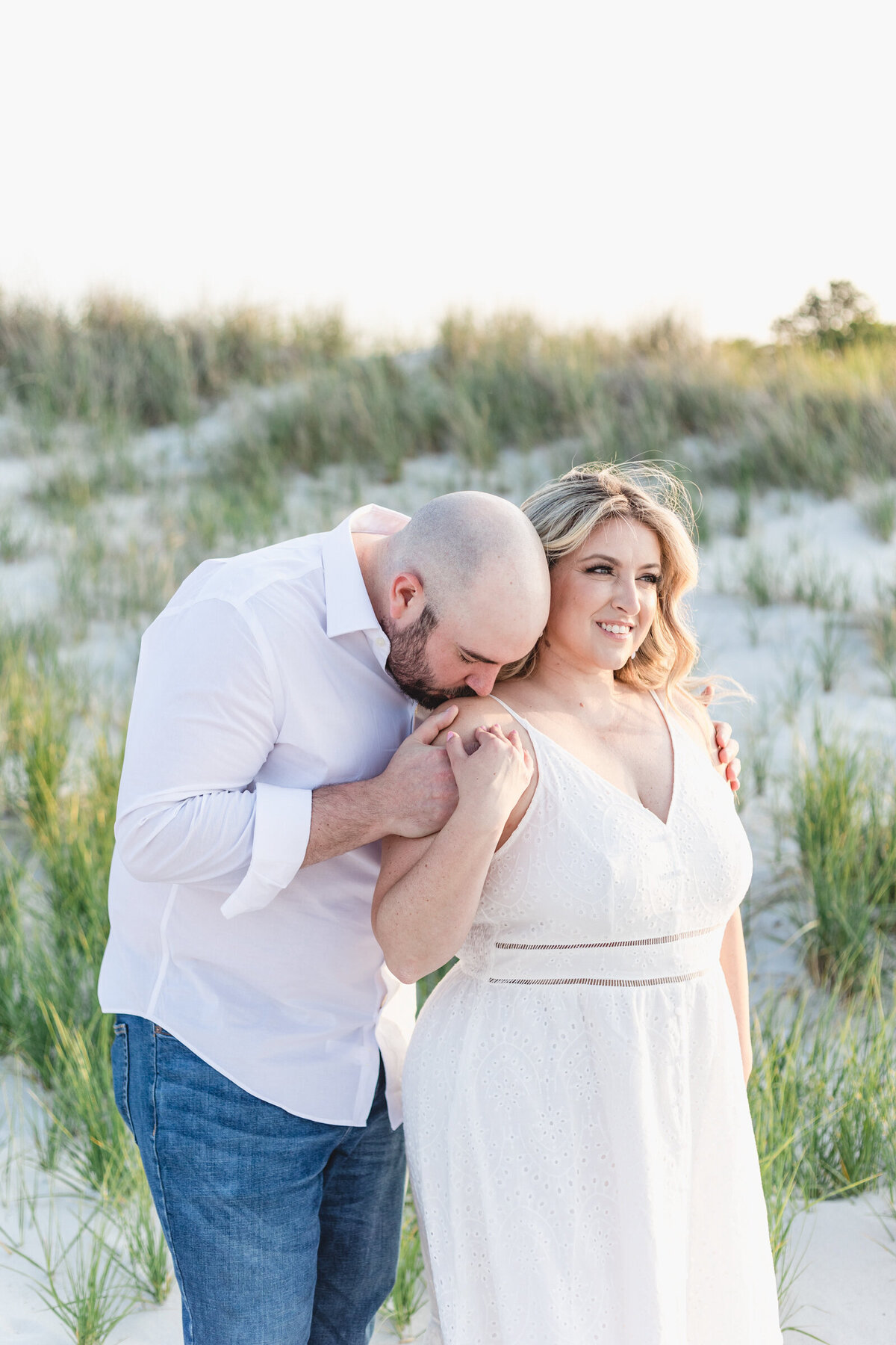 A man kisses his fiancee's shoulder during their engagement session on the North Shore