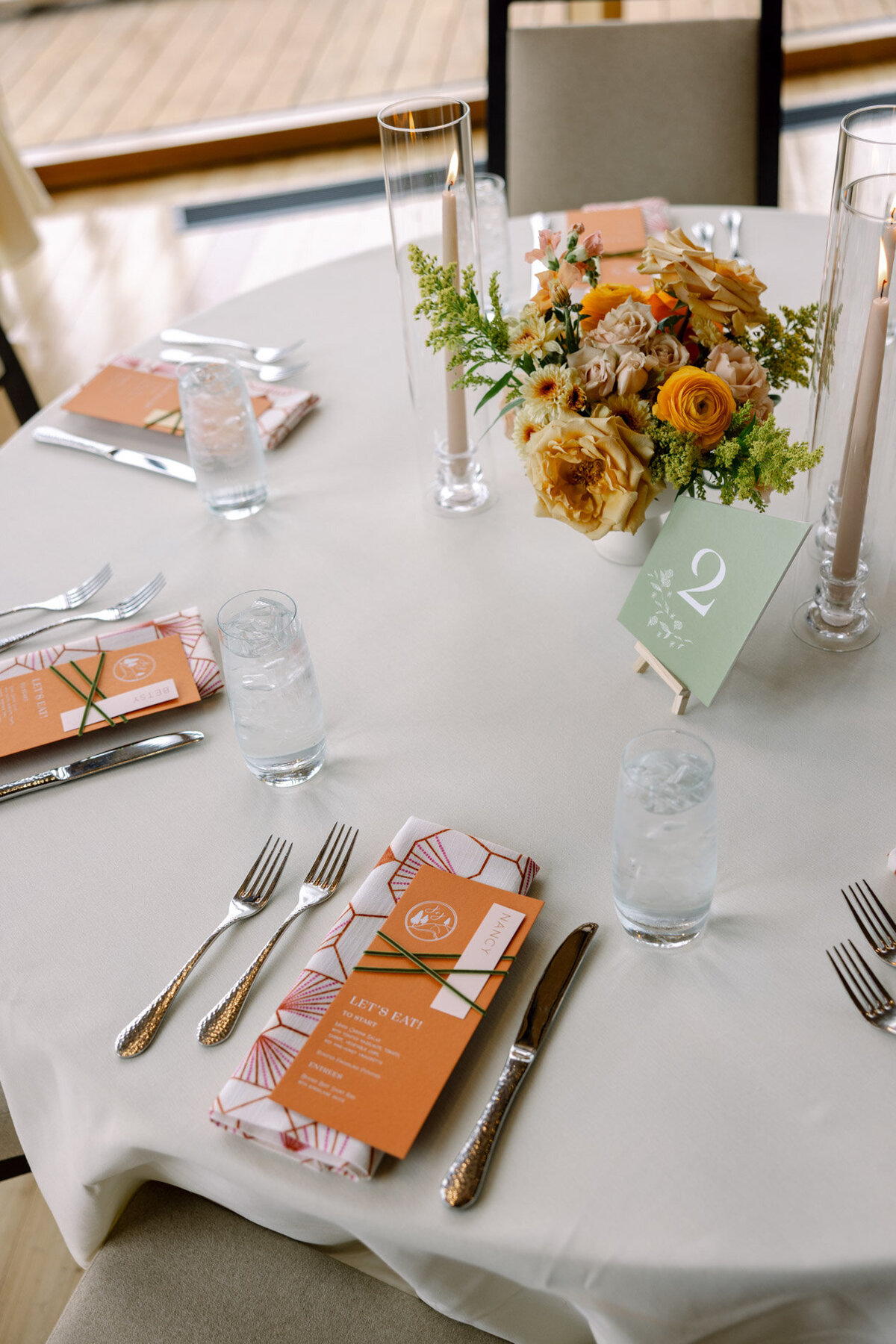 custom calligraphy wedding menu on a printed cloth napkin with florals and flatware representing full service design and calligraphy by Life in Letters.