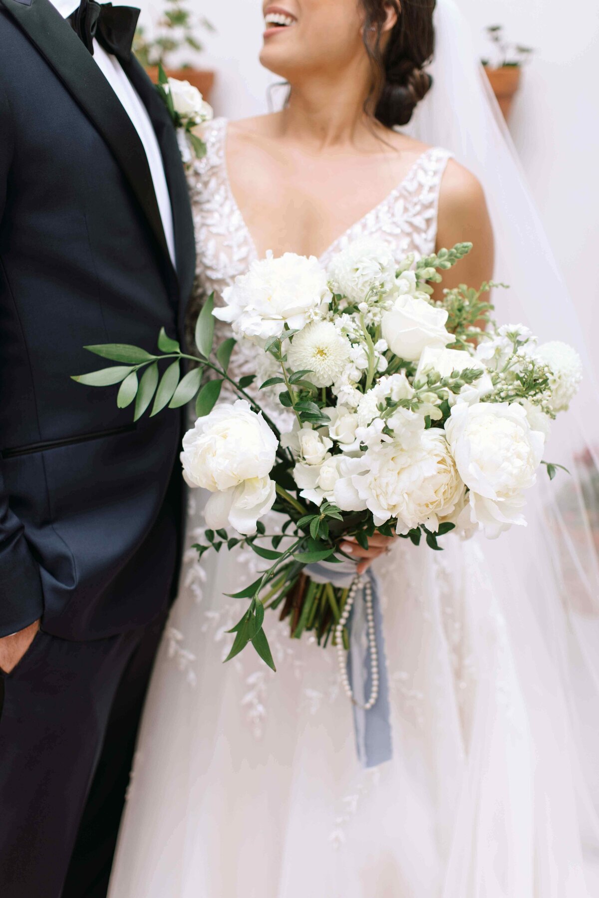 Bride holding a lush bouquet with white peonies