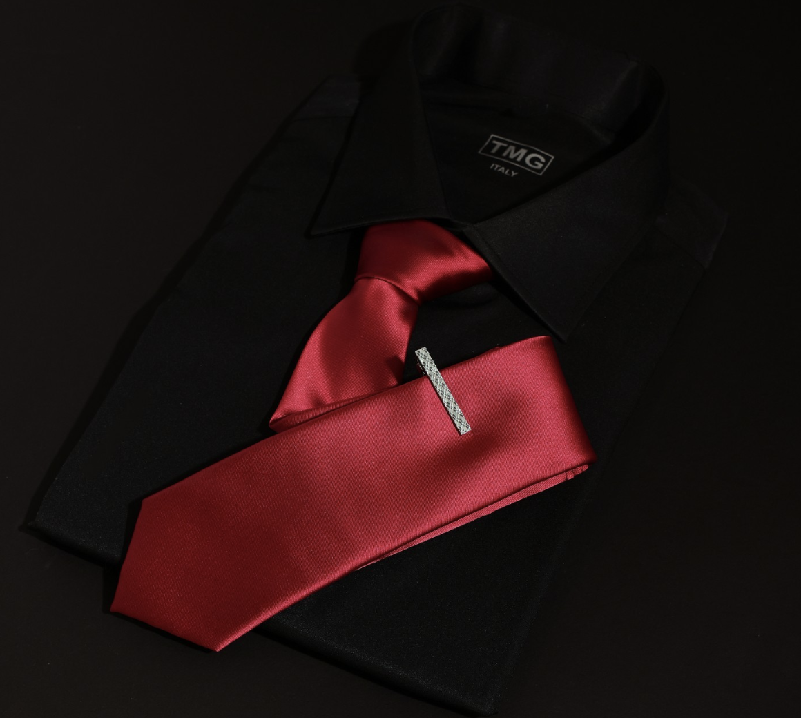 A red tie, silver tie bar, and black suit jacket representing suit accessories for men