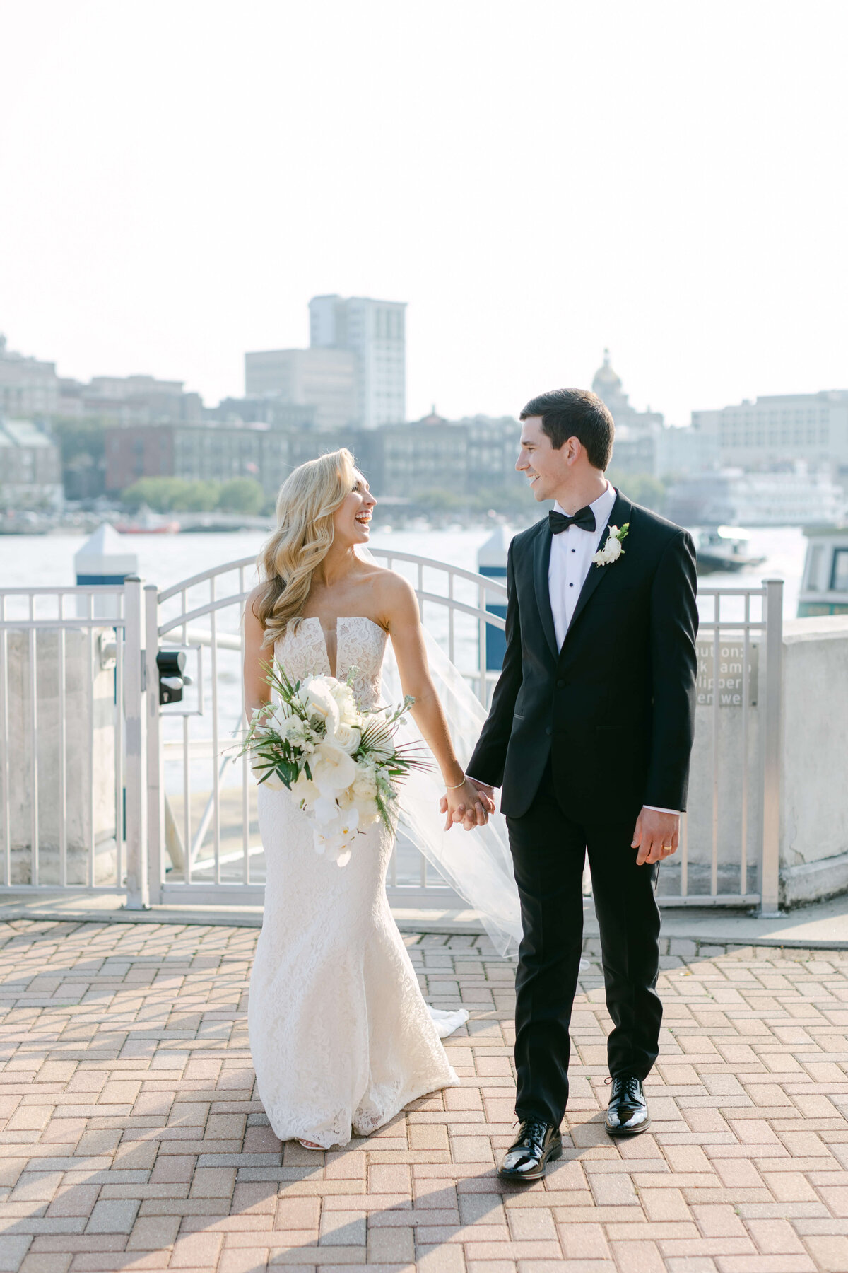 A bride and groom hold hands on the docks of Westin Savannah.