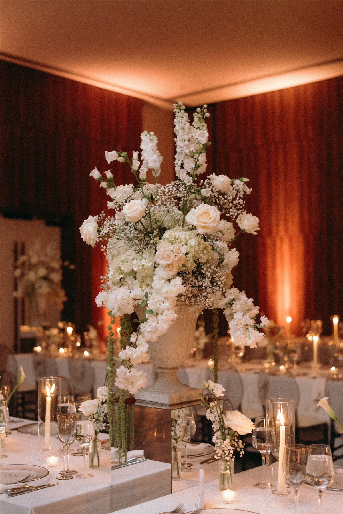 A large urn of elegant white flowers forms a classic centrepiece between tables at Westbury Ballroom.