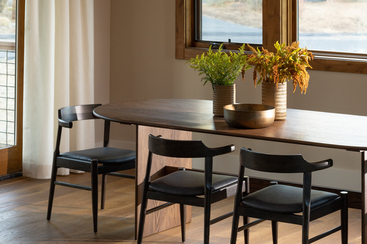 Dining area with wooden table and black chairs, captured through interior photography