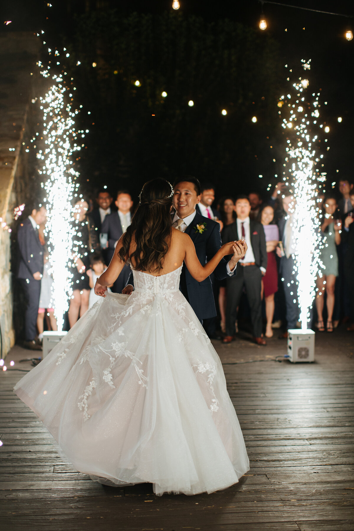 Bride and groom sharing their first dance surrounded by cold spark fountains and guests under string lights at Castle Ladyhawke.