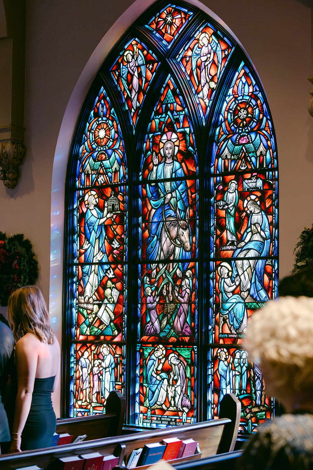 Colorful stained glass window towers behind couple during luxury church ceremony in San Antonio