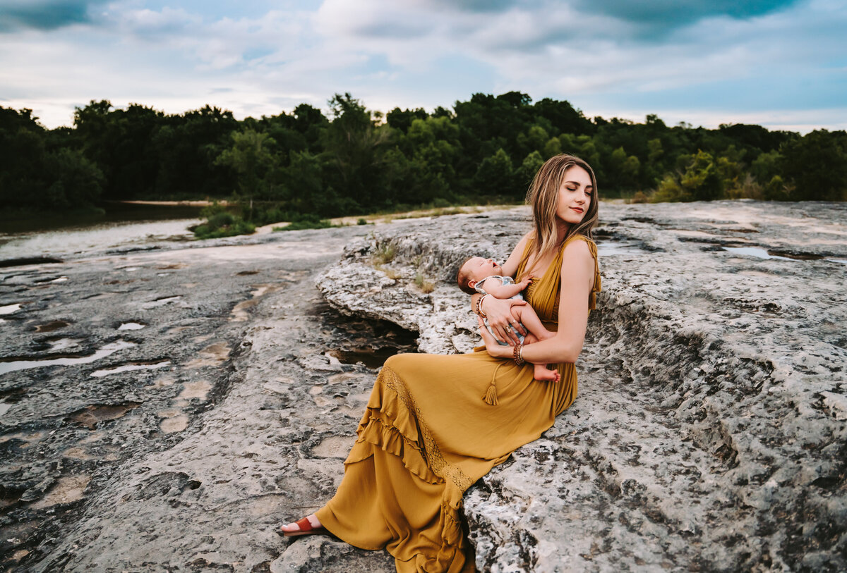 Family Photographer, a young mother holds her newborn child near beach and forest