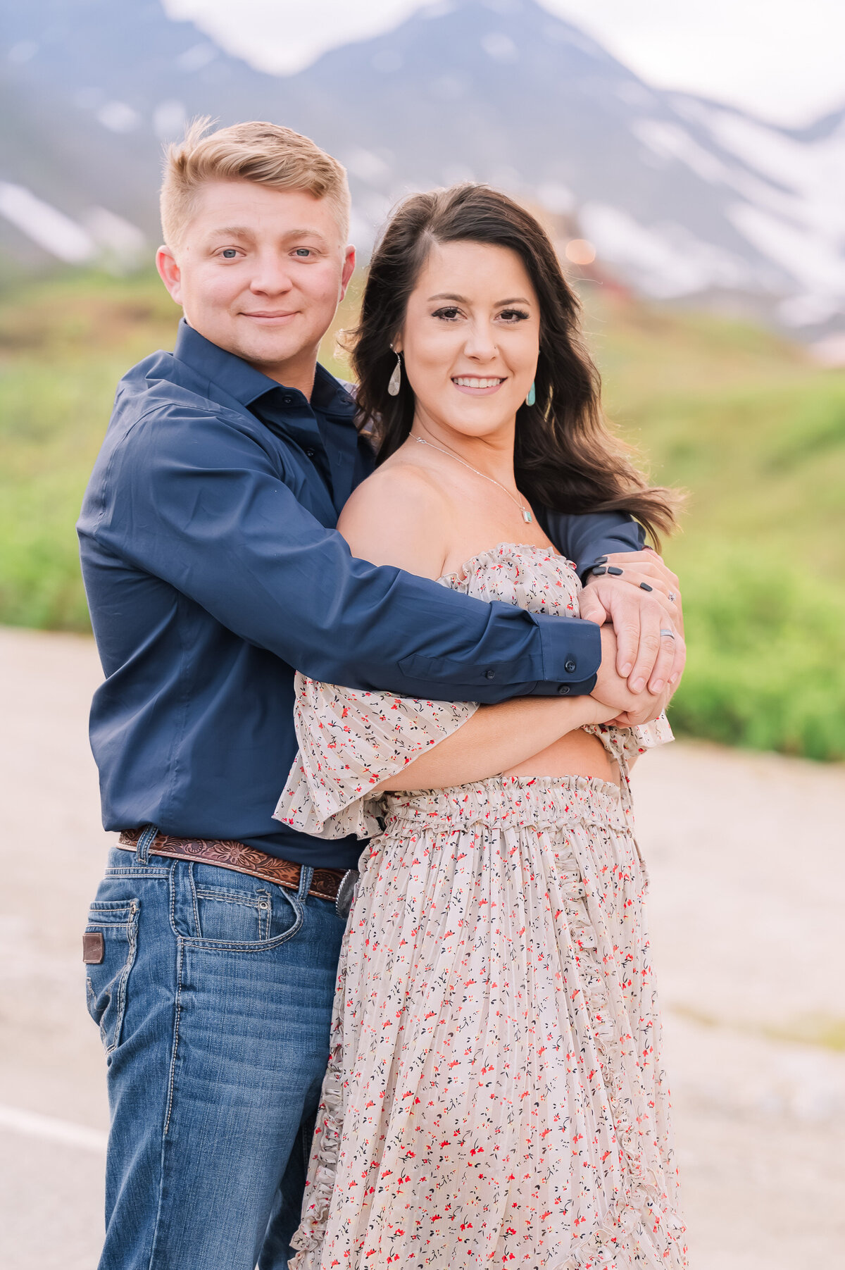 An engaged couple in western clothing smiling at sunset in Hatcher's Pass enjoying their summer engagement session