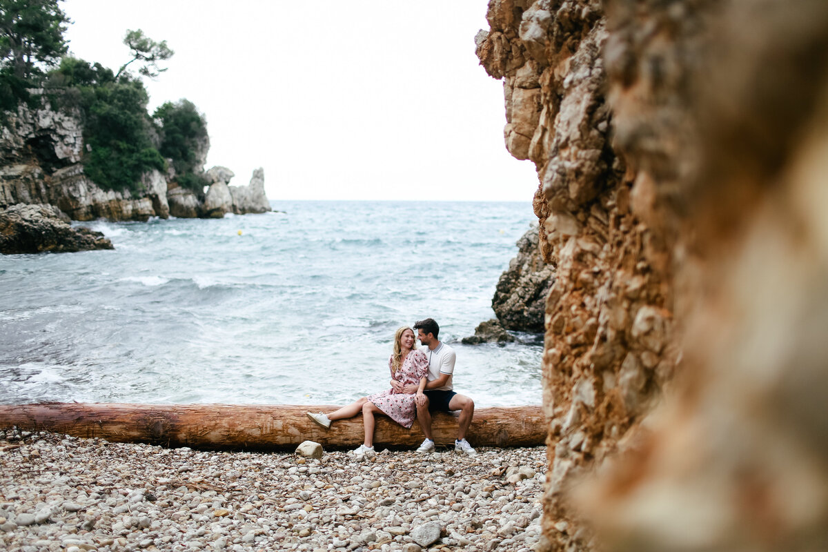 couple-sitting-on-the-beach-at-engagement-shoot-in-cap-dantibes