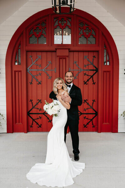 Bride and groom in front of red barn door to show planning a wedding in chicago