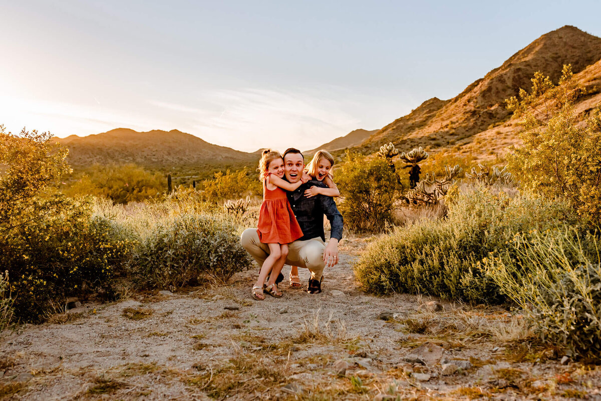 dad and daughters playing in AZ desert for family photographer