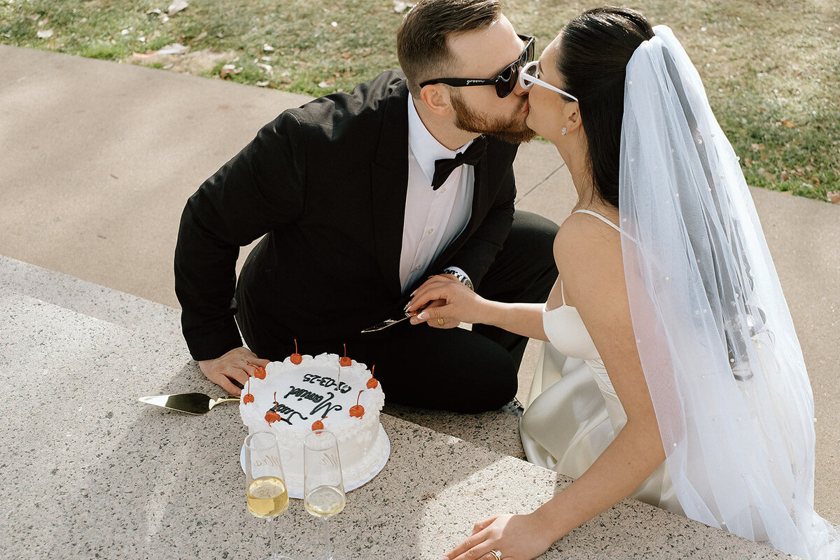 brid and groom kiss before cutting their cake together