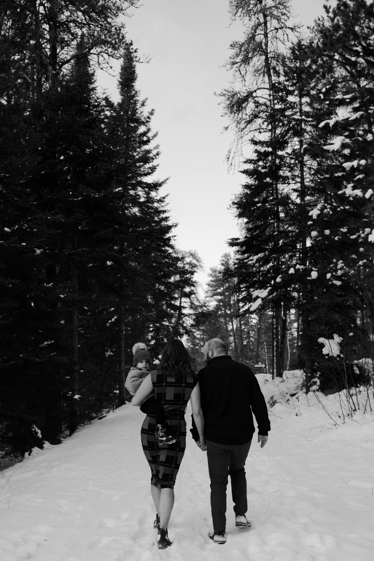black and white image couple walking in forest with child