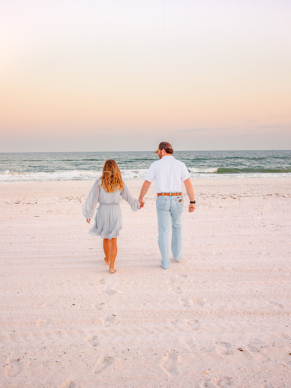 Couple walks toward sunset lit sky