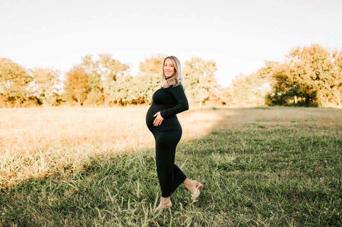 pregnant mom walking in field during maternity photography in Springfield MO