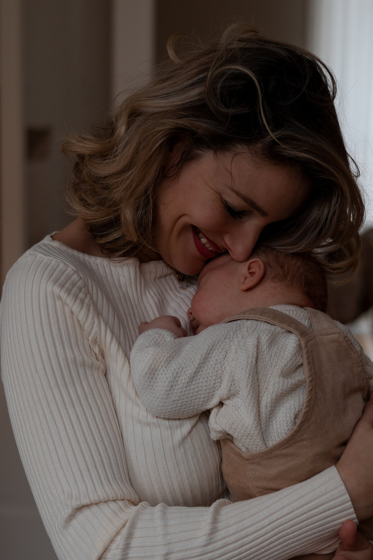 Een vrouw houdt een baby in haar armen, met een liefdevolle en zorgzame uitstraling.