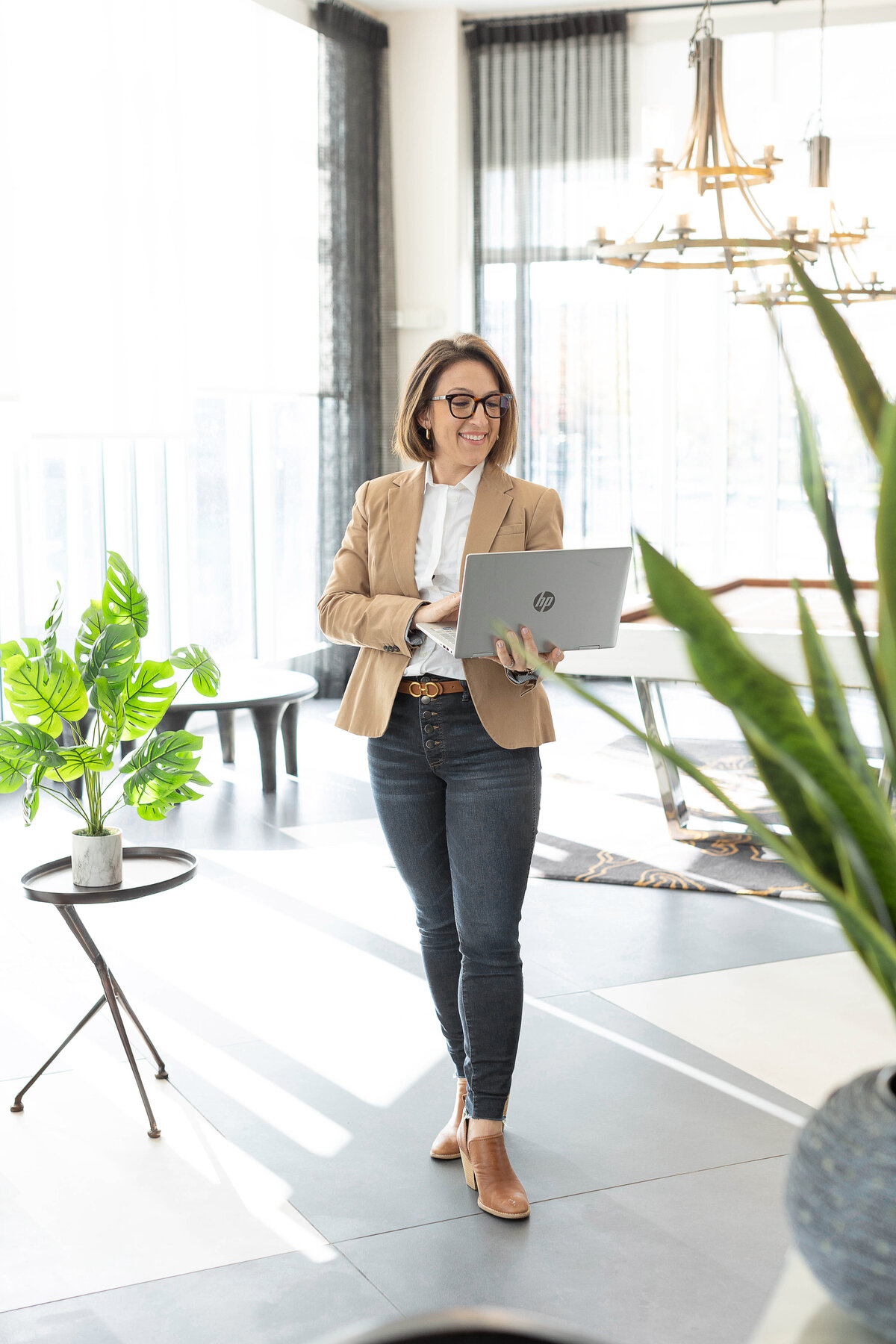 Woman holding laptop, standing in elegant space