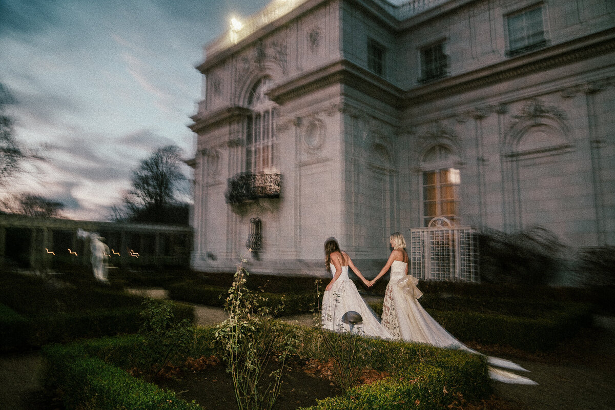 two brides walking in front of a newport rhode isalnd mansion. The mansion is Rosecliff mansion
