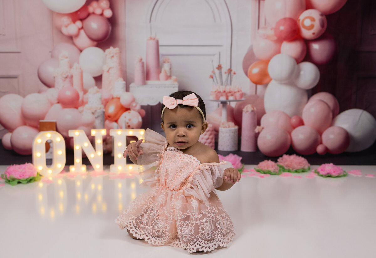 Sweet pink balloon-themed cake smash with baby girl in dress – First birthday photographer in Bergen County NJ