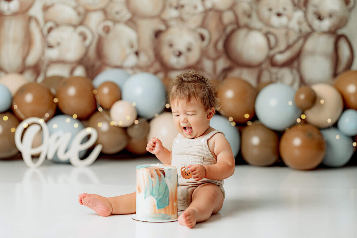 baby sticking out tongue after tasting first bite of smash cake
