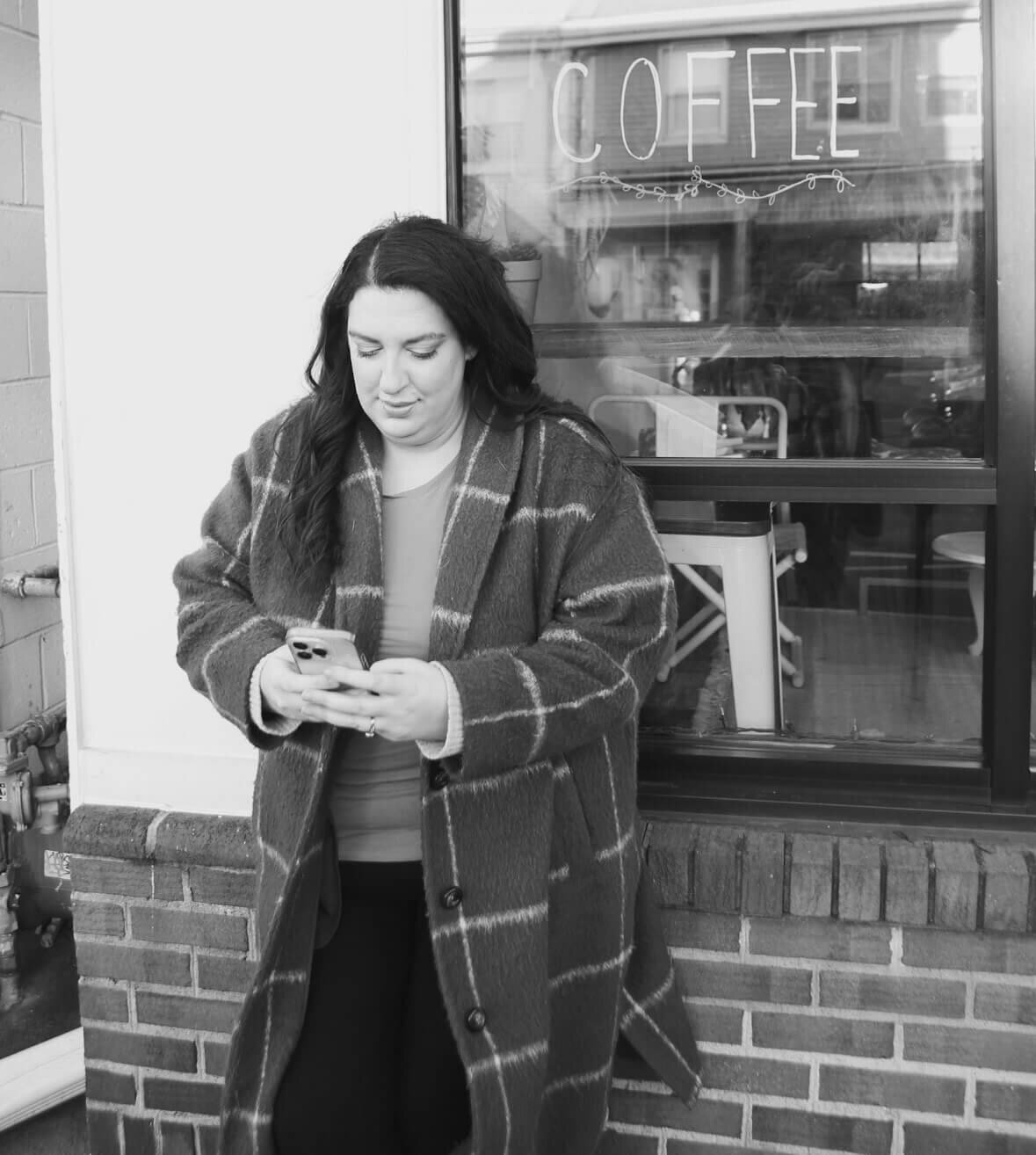 Black and white photo of Sarah Weiss looking at her phone