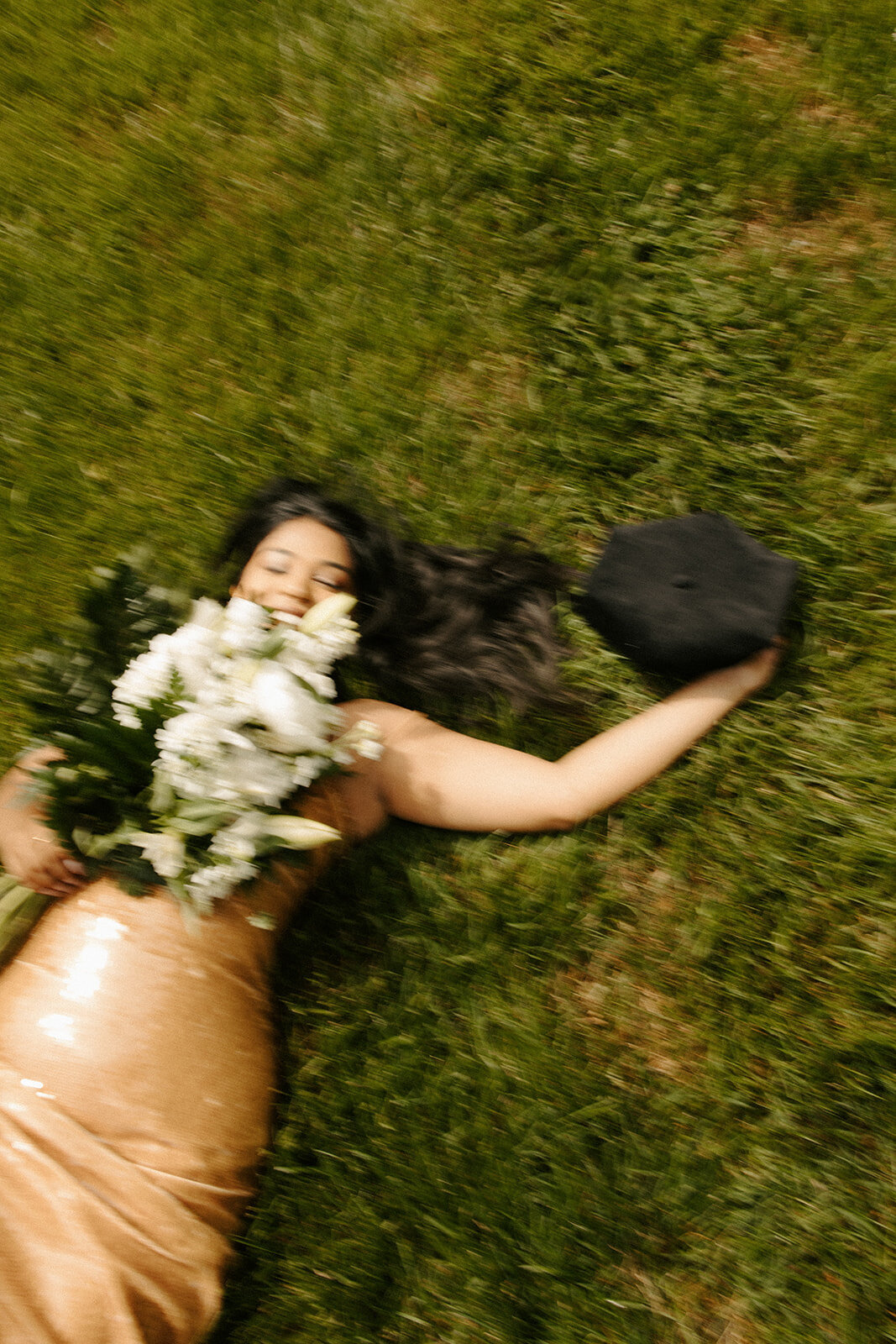 Graduate laying on the ground with flowers and graduation cap during graduation session from UVA Law
