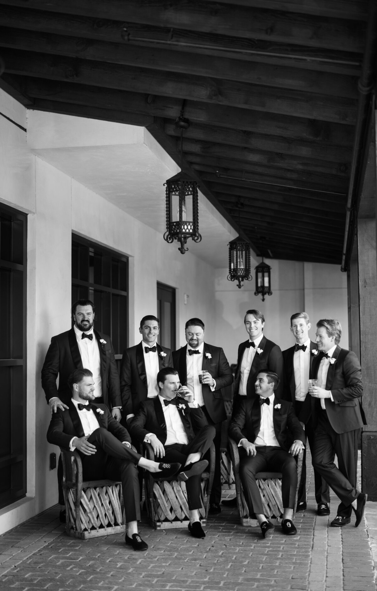 Groom and groomsmen sitting on a patio in black tuxedos