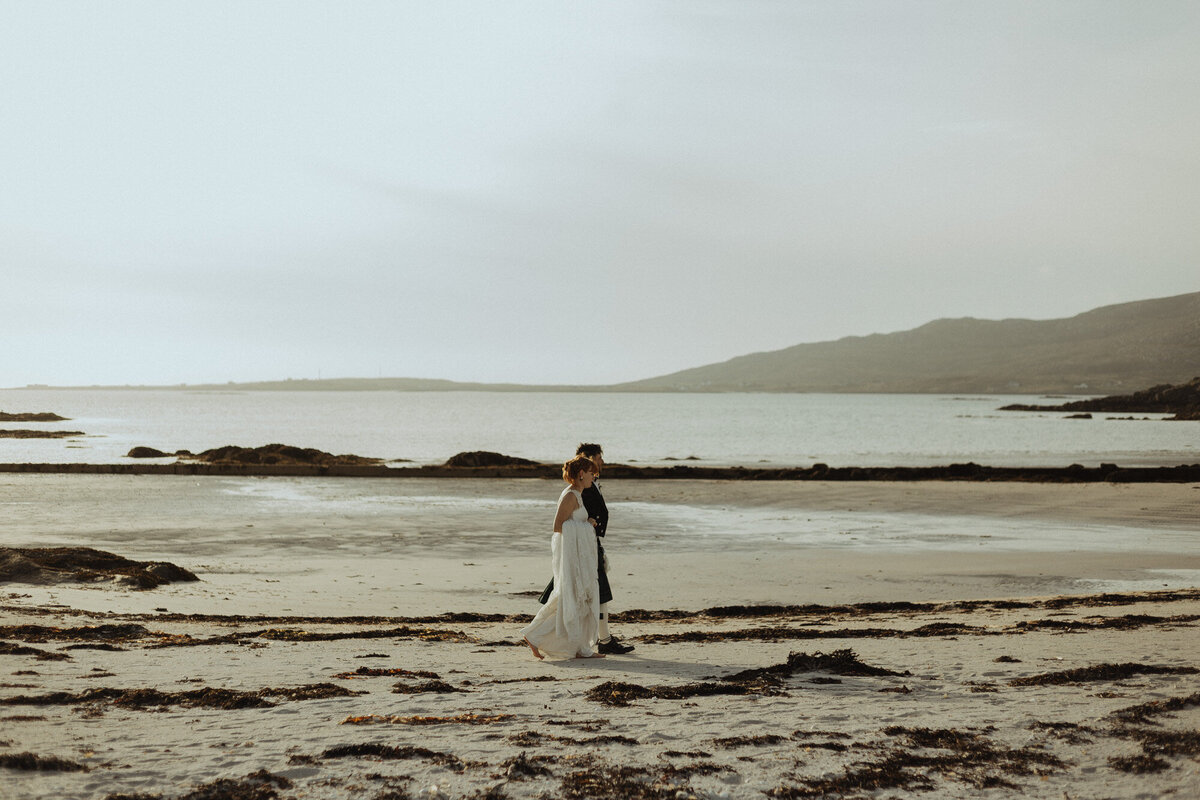 bride and groom walking on the beach at sunset