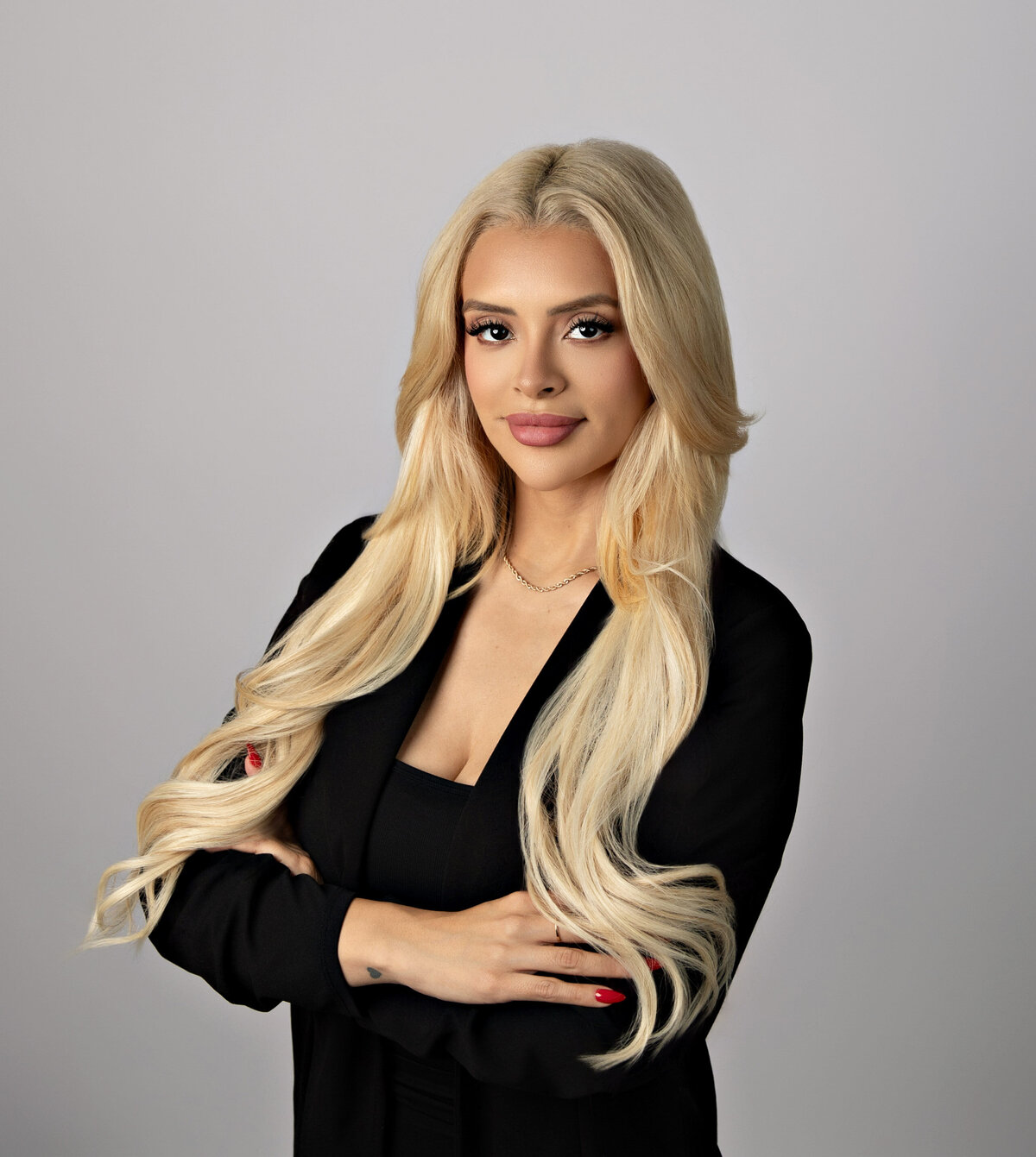 Woman in a black blazer and top, with long blonde curls and arms crossed, posing for a personal branding headshot—Eva Magaña Photography, San Antonio.