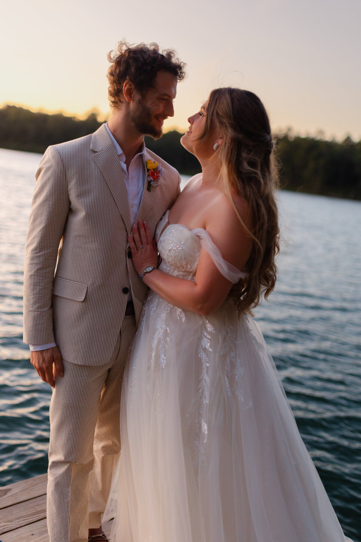 The newlyweds smile at each other on a dock after their outdoor wedding with a Duluth photographer, S Jacobson Photography.