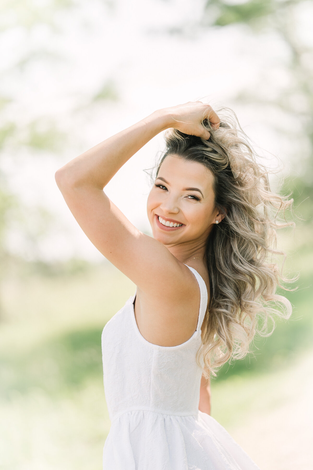 Senior smiles and plays with hair with Louisiana Senior Photographer.