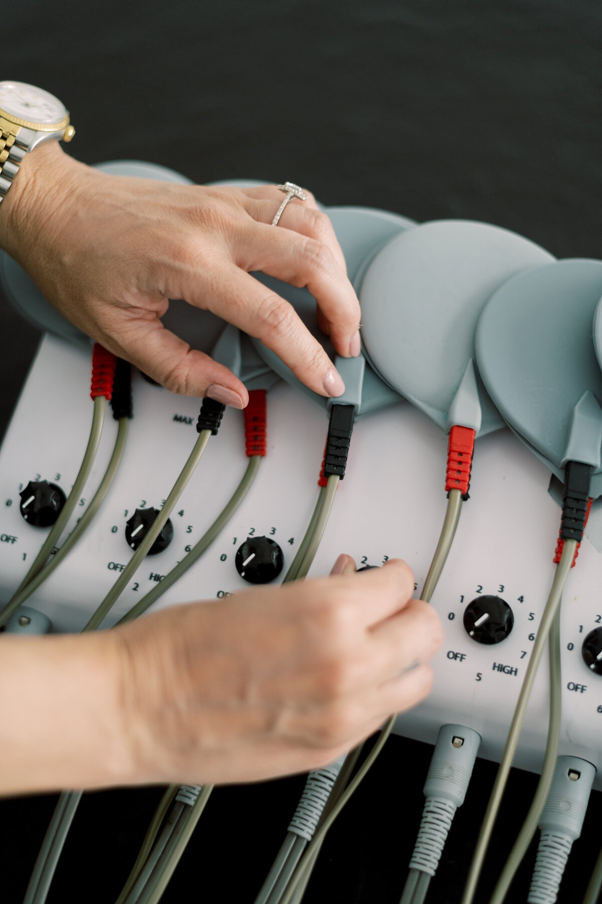 Close-up of woman's hands adjusting dials on body sculpting machine
