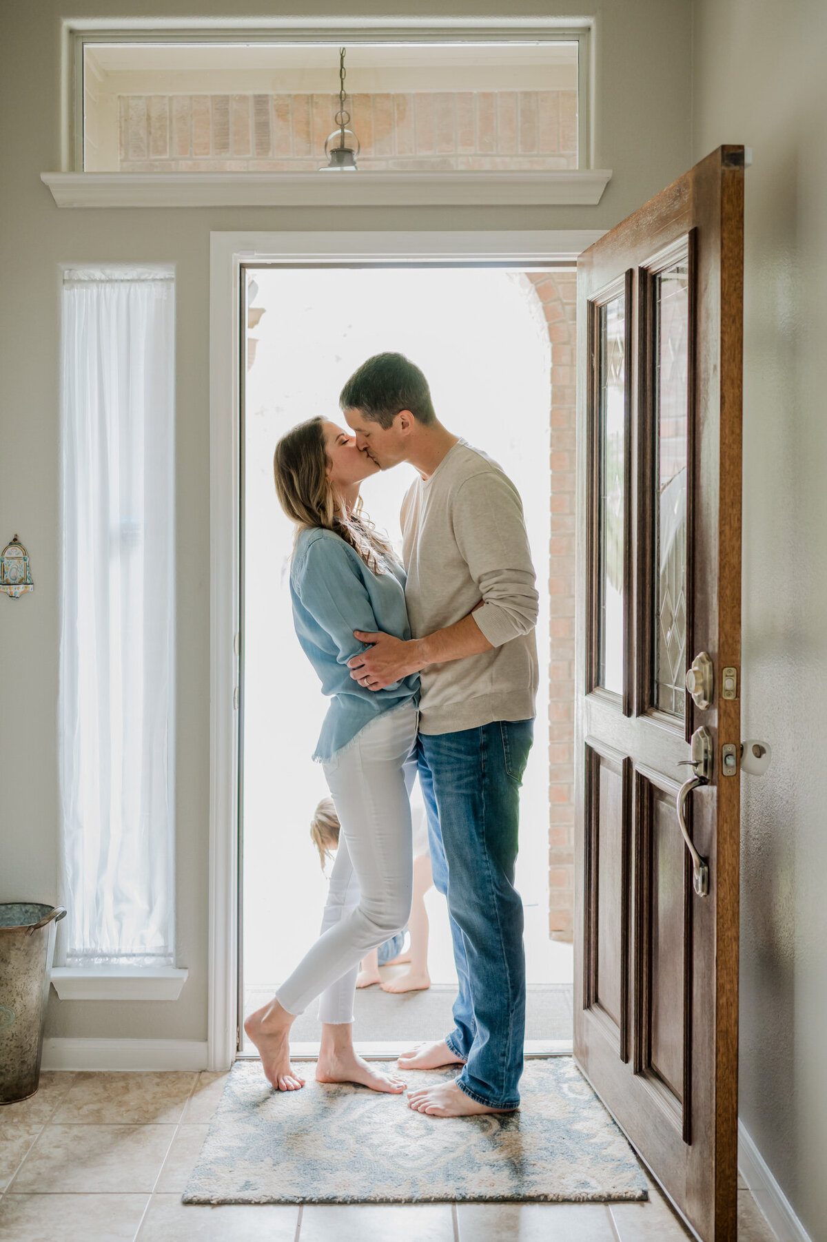 Backlit image of a couple kissing inside their open front door.