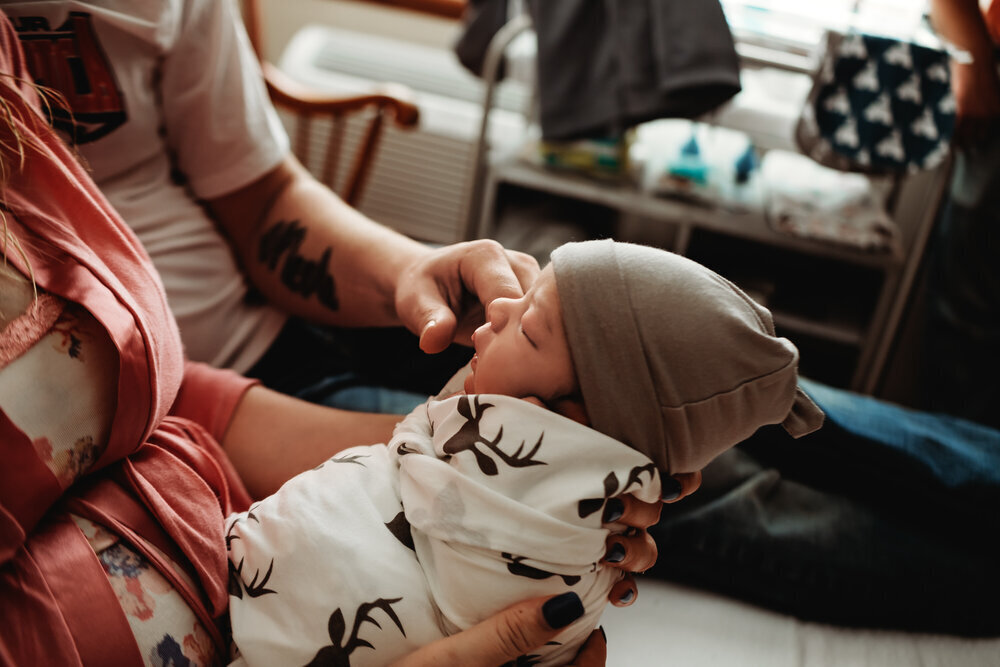 a young mother holds her newborn son in the hospital