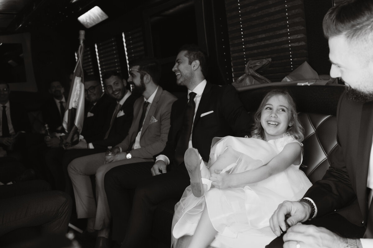 little girl laughing with wedding party as she puts on her shoes in the limo