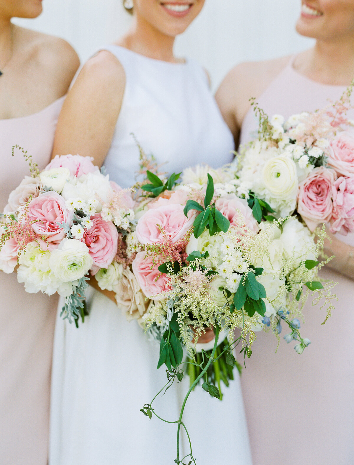 Bride and bridesmaids holding white, pink and green bouquets