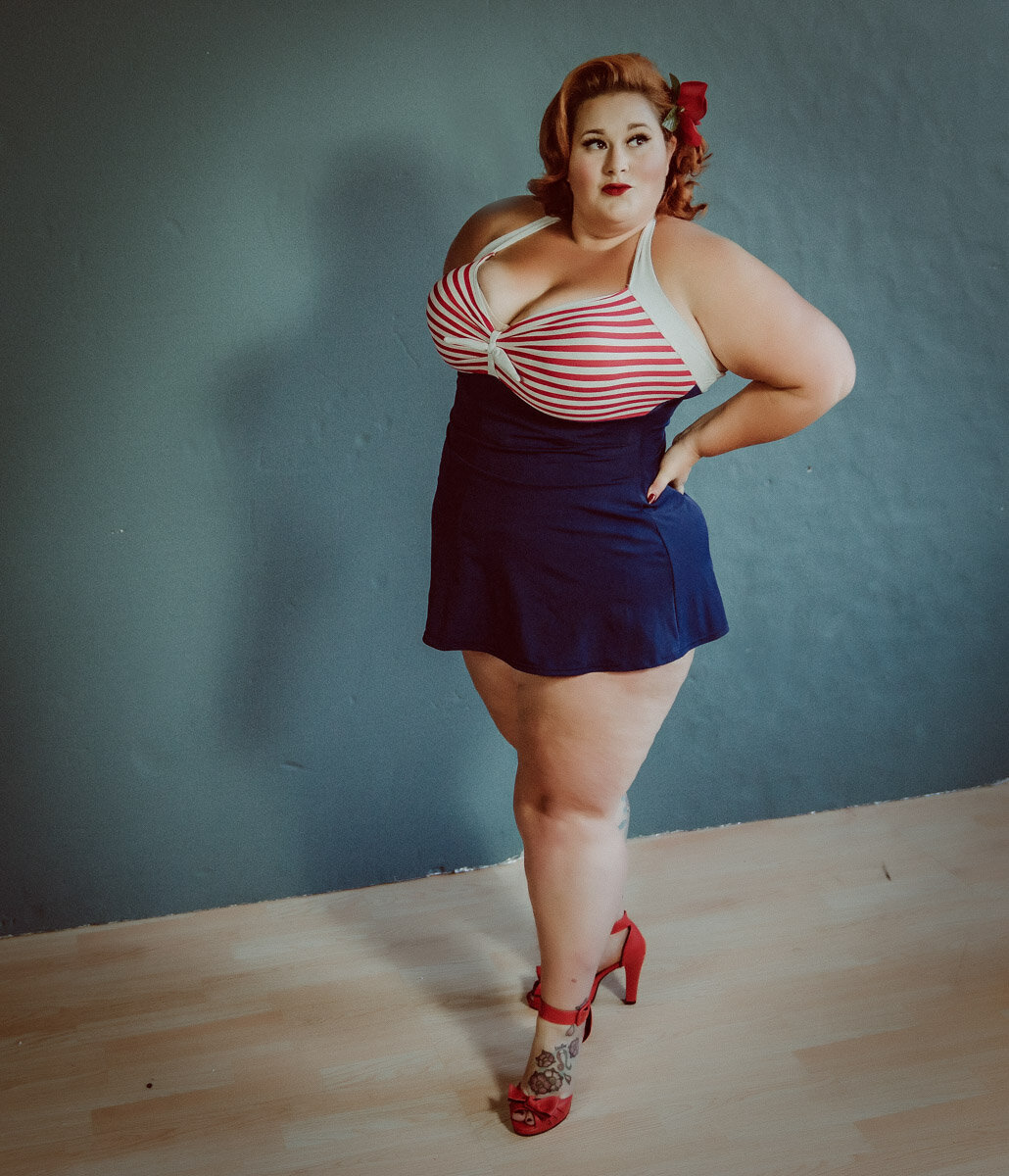 Woman wearing pinup red whit and blue swimsuit with red flowers in her hair in the twin cities