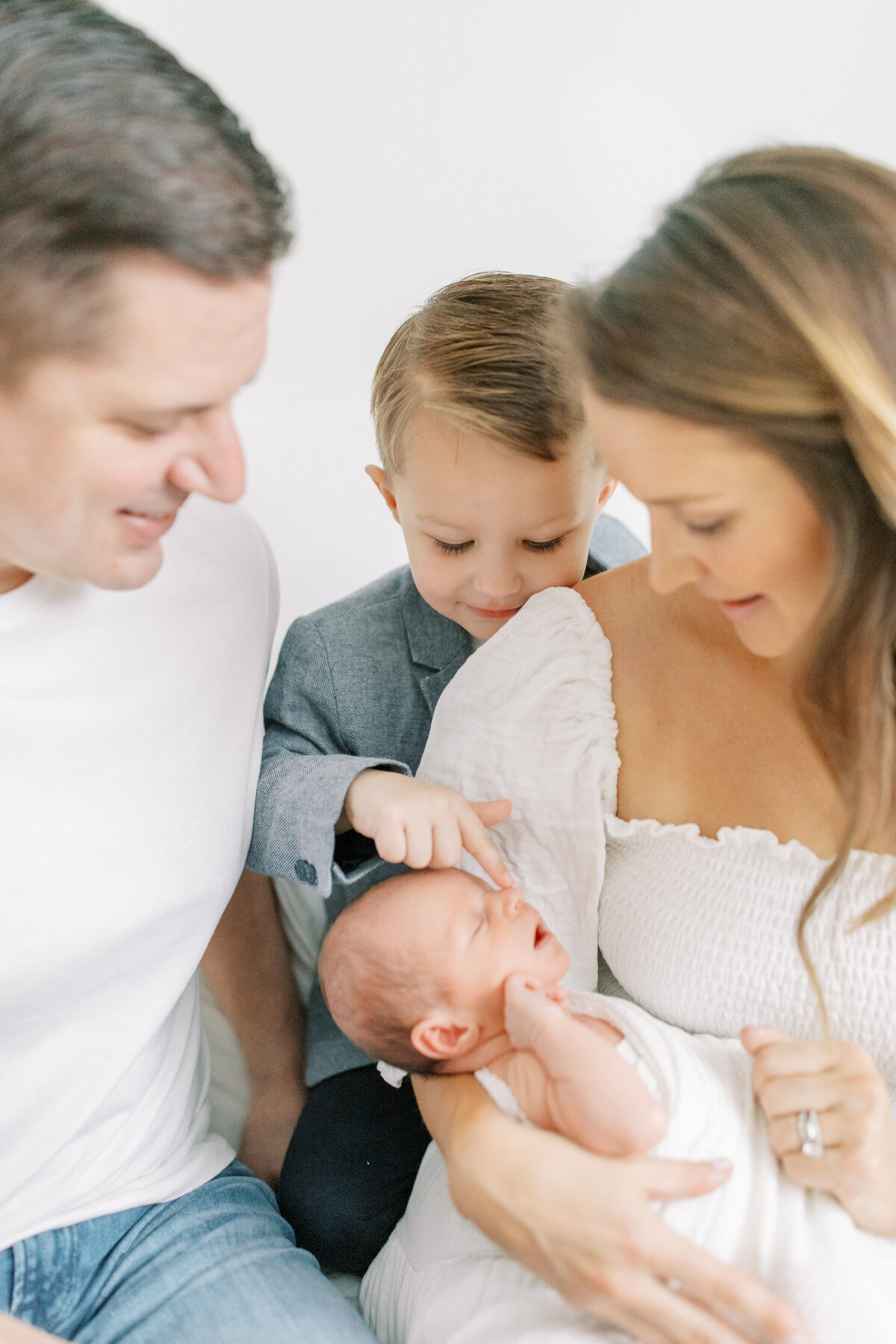 family with newborn and son touching his nose by photographer in spokane wa