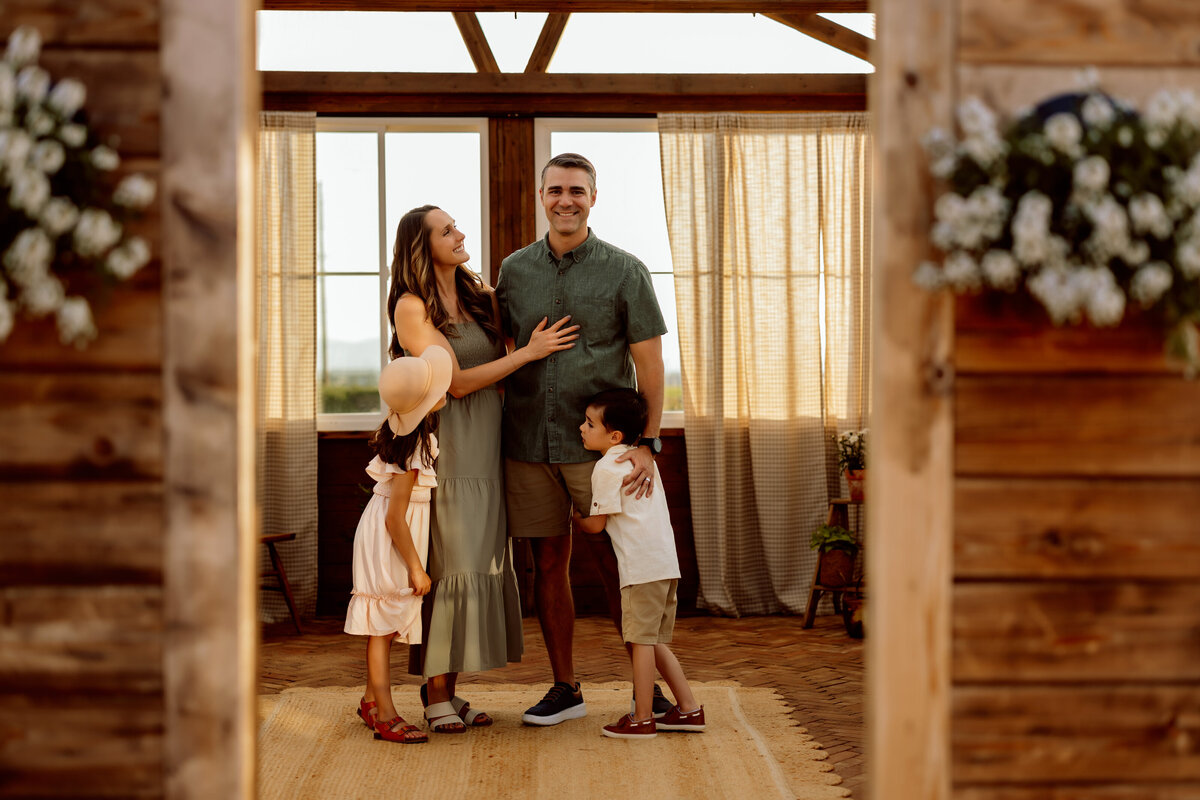 Beautiful family stands together in the middle of a greenhouse during the summer for their family photo session in Denver