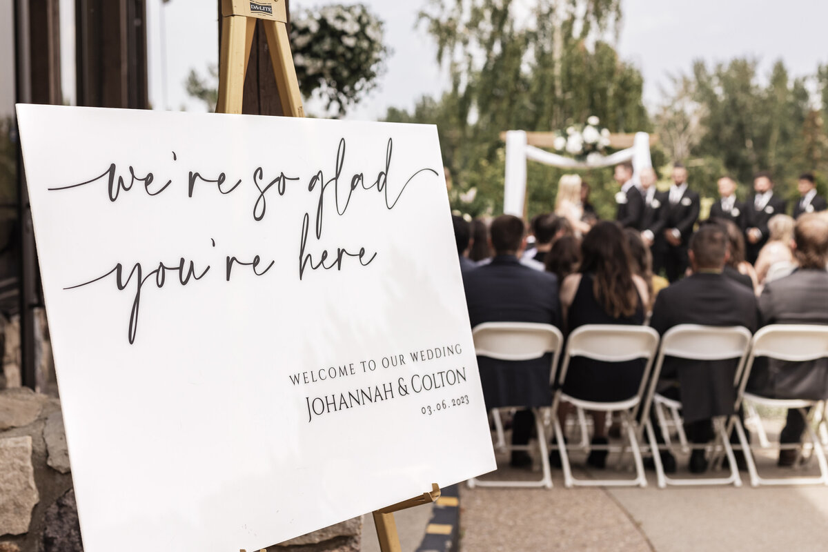 Wedding welcome sign with ceremony going on in the background