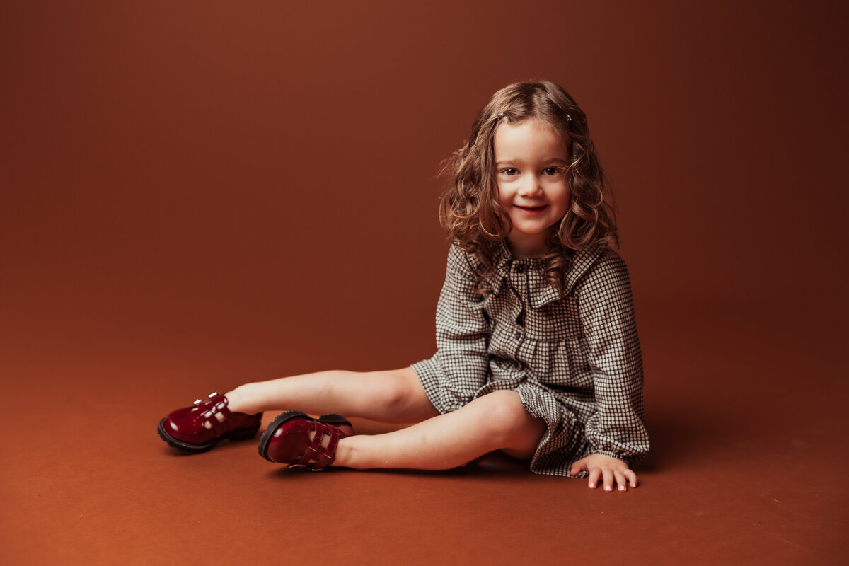 girl-sitting-brown-studio-backdrop